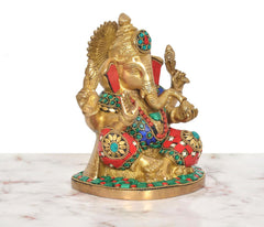 Close three-quarter view: brass Ganesha with red cloth, turquoise round inlays, detailed hands