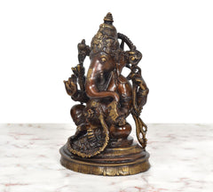 Brass Ganpati Bappa murti, left profile of seated four-armed deity with halo