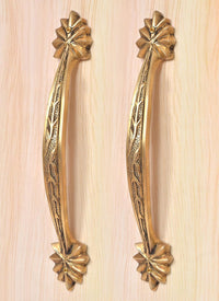 Golden brass door handle pair with engraved leaf pattern and four-petal rosette accents at ends.