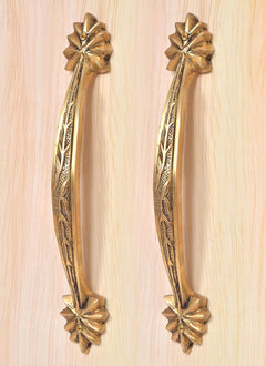Golden brass door handle pair with engraved leaf pattern and four-petal rosette accents at ends.