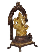 Brass Ganesha idol statue with ornate arch, golden finish, seated on dark pedestal