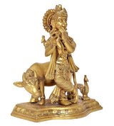 Krishna flute statue in brass tone, standing on cow with small figures, detailed base