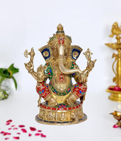 Brass Ganesh idol with raised hands, colorful jeweled robes, blue base