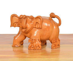 Side view wooden elephant showpiece with carved mini figures at feet, orange-brown