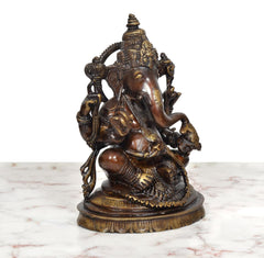 Brass Ganpati Bappa murti, three-quarter view showing trunk, arms and golden accents