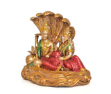 Close view of Vishnu and Lakshmi figurines seated on Sheshnag, green and red drapes