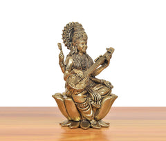 Brass Maa Saraswati figurine seated on lotus, veena in lap, angled view.
