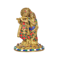 Brass Radha Krishna idol close-up, raised hands and jeweled red-blue clothing on base