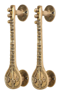 Close-up of sitar-shaped golden brass door handles with round rosettes and finials