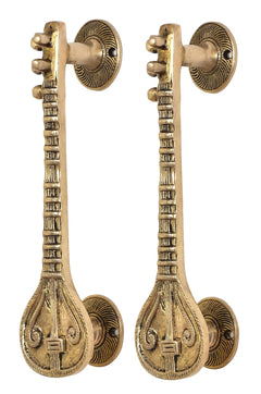 Close-up of sitar-shaped golden brass door handles with round rosettes and finials
