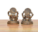 Back view of two sitting resin murtis—Lakshmi and Ganesh—with textured gold-toned detailing