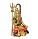 Brass Shiva murti, seated with trident, red-and-blue outfit, gold ornaments