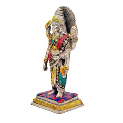 Dhanvantari brass statue in profile view; red-and-teal robe with gold trim on patterned base.