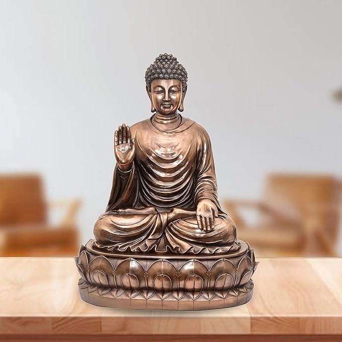 Resin Buddha idol, seated with one hand raised, detailed robe and lotus base