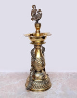 Brass peacock oil diya stand side view with flared top dish and detailed body patterns