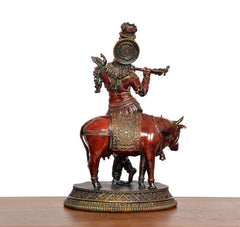 Brass Krishna idol on cow, back/side view with large halo ornament and decorative panel