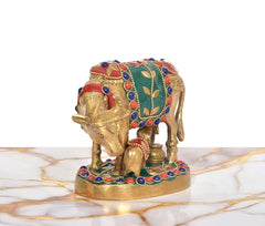 Brass cow with calf idol, rear angle; green cloth panel with golden leaf motifs