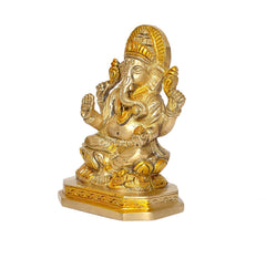 Brass Ganesha idol, side view, curved trunk and ornate jewelry on pedestal
