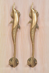 Two golden brass dolphin fish door handles with round base plates