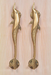 Two golden brass dolphin fish door handles with round base plates