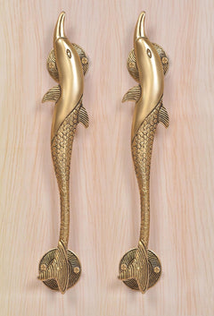Two golden brass dolphin fish door handles with round base plates