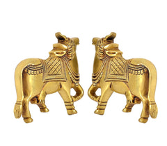 Brass cow pair statues, front-facing stance with ornate neck and saddle designs