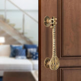 Brass sitar-shaped door handle pair with round rosettes and ornate carved stems.
