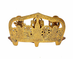 Back view of gold-toned metal diya with ornate openwork arch and raised feet
