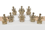 Brass Lakshmi idol set of 8, group view of seated figures with raised hands