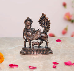 Copper Kamadhenu cow statue with wings, detailed metalwork, standing on round base.