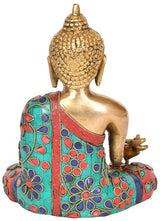 Gold Buddha idol from side view, multicolor embroidered robe, open hand pose