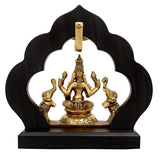 Brass Maha Lakshmi idol framed by dark temple arch, seated with elephant attendants