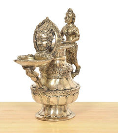 Brass oil lamp with side view deity holding a wide flame bowl on pedestal base