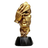 Gold polyresin human face ornament, raised hand, black pedestal base, front angled view