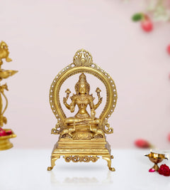 Brass Lakshmi seated statue with prabhavali, four-armed goddess detail