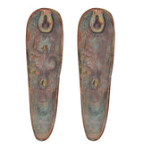 Bronze-green backs of tribal face plaques, two hanging loops at the top