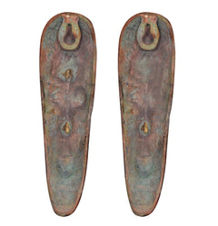 Bronze-green backs of tribal face plaques, two hanging loops at the top