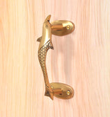 Angled view golden brass dolphin fish door handle with side fins and mounting plates