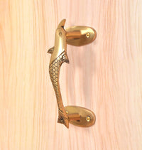 Angled view golden brass dolphin fish door handle with side fins and mounting plates