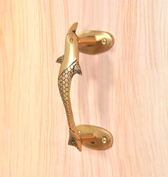 Angled view golden brass dolphin fish door handle with side fins and mounting plates
