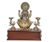 Lakshmi brass goddess idol back view, peacock oil lamps on raised wooden base