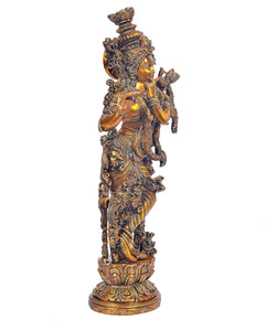 Brass Krishna idol side view holding flute with layered ornaments on pedestal