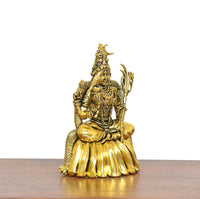 Golden brass deity statue seated on lotus base, ornate crown and side ornaments