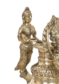 Brass deity oil lamp figure holding a small flame bowl, carved ornamental clothing