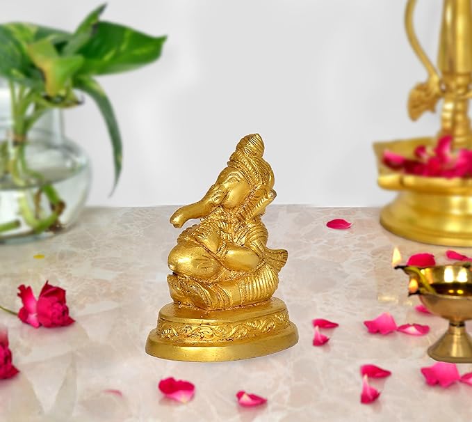 Gold Ganesha idol statue, seated with ornate details and circular base