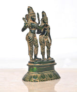 Brass dancing idols of Shiva and Parvati, green-and-gold attire, raised pedestal base