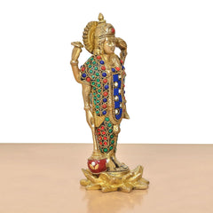 Brass Vishnu idol profile view, colorful bead ornaments on robe, red ornament at feet.