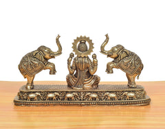 Rear view brass Lakshmi statue showing crown and draped outfit, elephants flank the seat