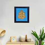 Brass Ganesha wall art in dark wooden frame with blue backing