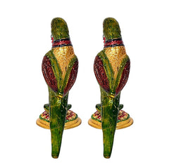 Front view of two iron parrot statues with green bodies, red bands, on gold bases